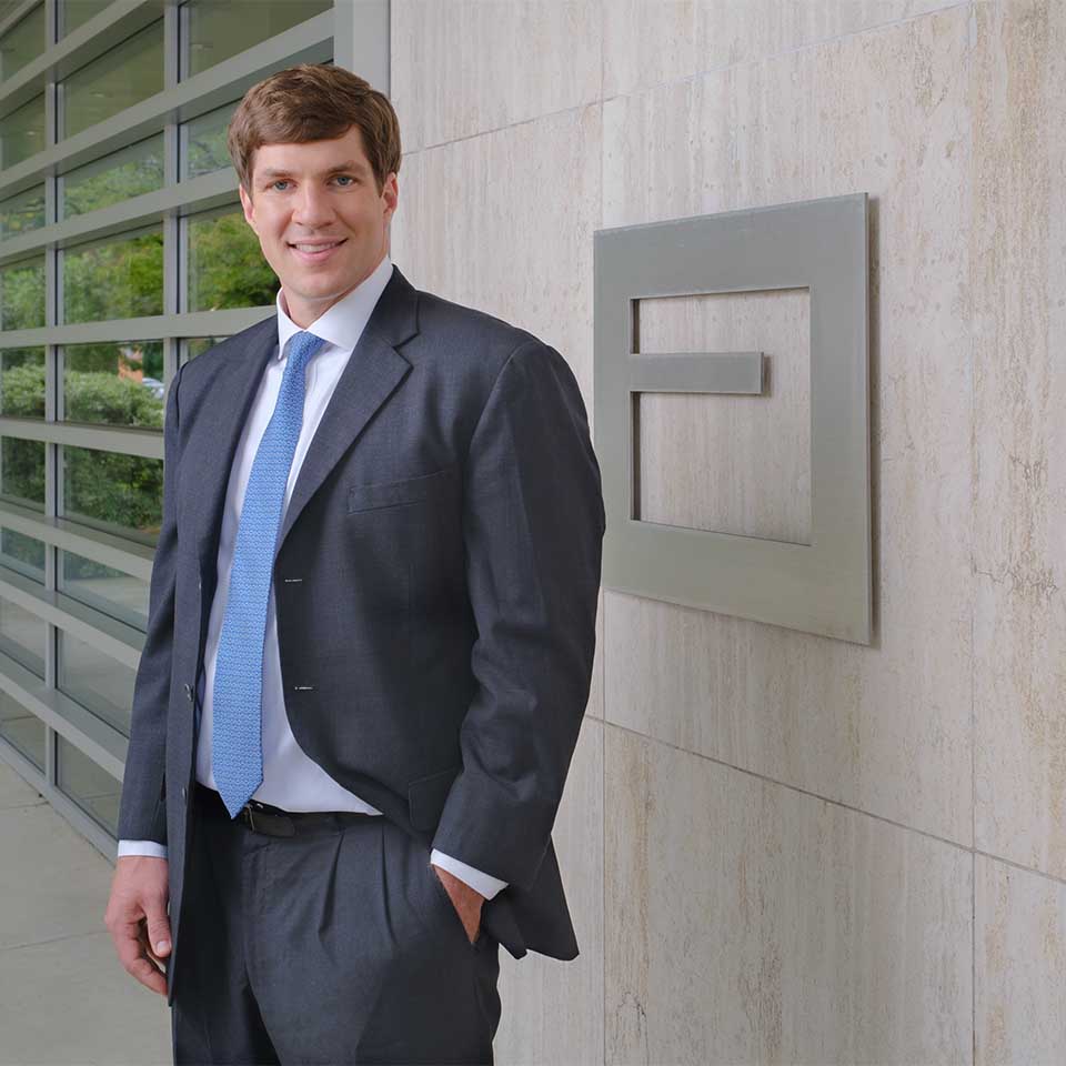 William Jeter standing outside of the Devine Street office in front of a wall of floor-to-ceiling windows and a stainless steel abacus logo.