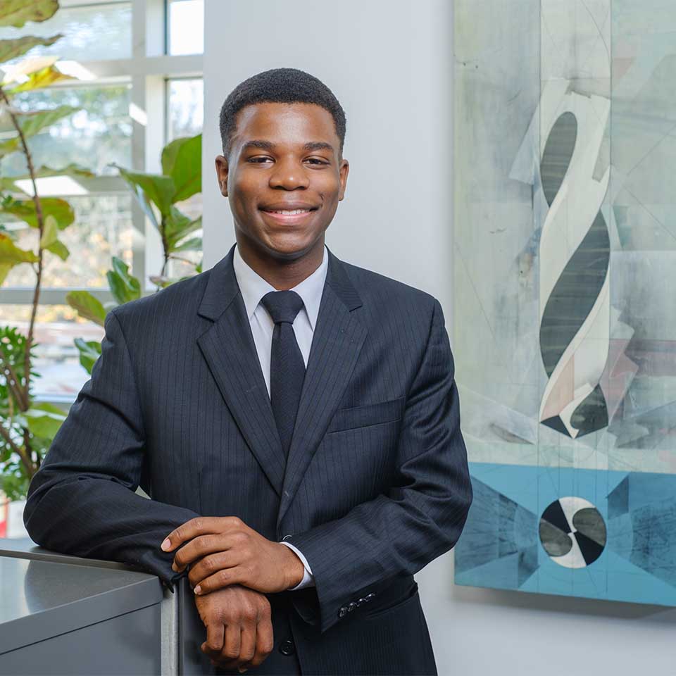 De’Quae Craft standing next to a counter in front of an abstract painting of a drill.